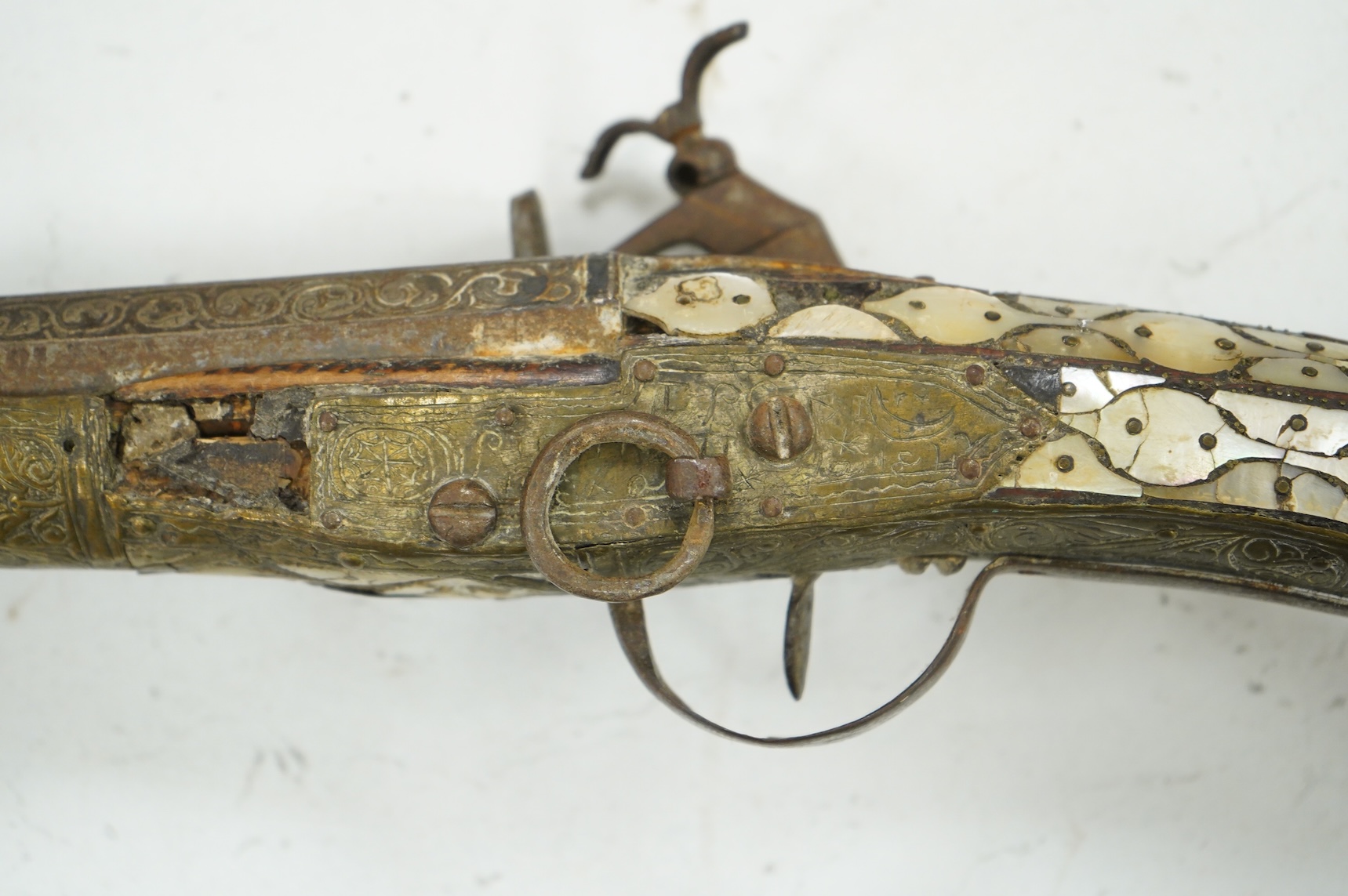 A Balkan miquelet flintlock gun with part octagonal Damascus twist barrel, silver inlaid at breach and muzzle, brass covered stock with shaped mother-of-pearl segments covering the butt, the side of stock inscribed ‘Piet